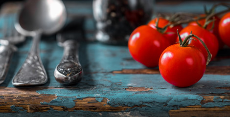 Cutlery and cherry tomatoes on an old table.