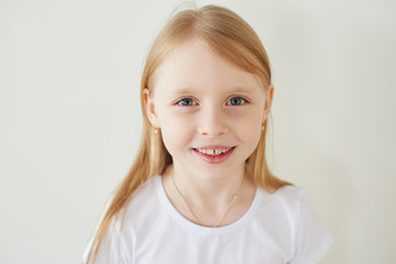 Portrait of little blonde girl on white background in white t-shirt