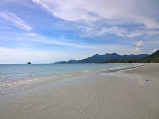 Blue sky and clouds over a tropical beach with green palm trees on Koh Chang island in Thailand