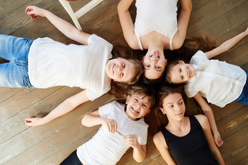 Children are in a circle. Five girls on the wooden floor top view.