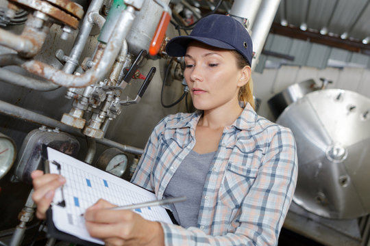 female maintenance worker testing brewery machine at brewery - Powered by Adobe