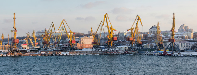 Panorama of the sea port in winter. Port cranes and tug at the pier in the snow