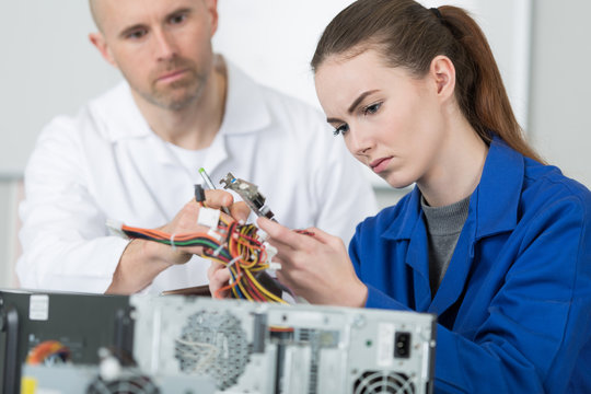 man looking for woman trainee fixing computer at work