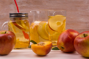 Refreshing cold detox from apples, peaches and citrus fruits in a glass on a table with fruit