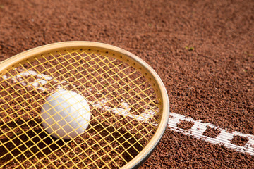 tennis raquet with tennis ball on ash court