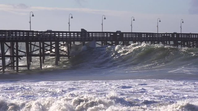 Huge waves crash on a California beach and pier during a very large storm event.