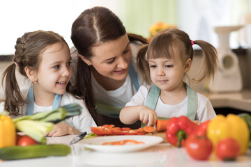 Happy mother and her kids daughters enjoy making healthy meal together
