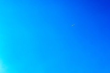 Airplane flying in the blue sky among clouds and sunlight