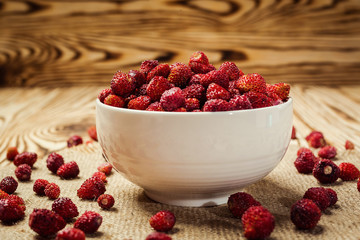 red strawberries in bowl on a wooden background