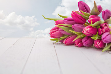 Bunte Frühlingsblumen auf einem Holztisch vor blauem Himmel
