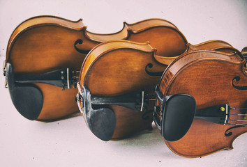 The classic old film design background of wooden violin,three violins stacked on board,warm light...