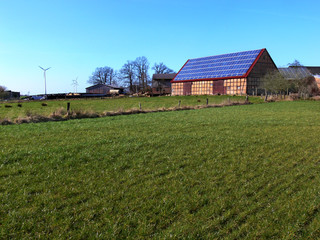 Photovoltaik-Anlage auf einer alten Scheune mit Wendland-Fachwerk , davor eine grüne Weide
