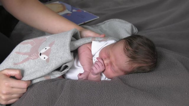 newborn baby being rubbed to sleep by mom