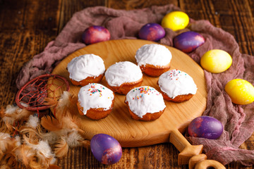 Cupcakes on a decorative board and unusually painted in yellow and purple colors Easter eggs.