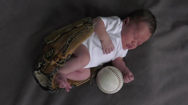 newborn baby in baseball glove wiggling around top view cute