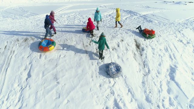 The children are playing and rolling down a hill on snow inflatable sled