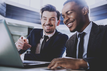 Two young businessmen are working with laptop in modern office