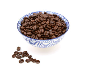 Roasted coffee beans in a bowl, some spilled beside