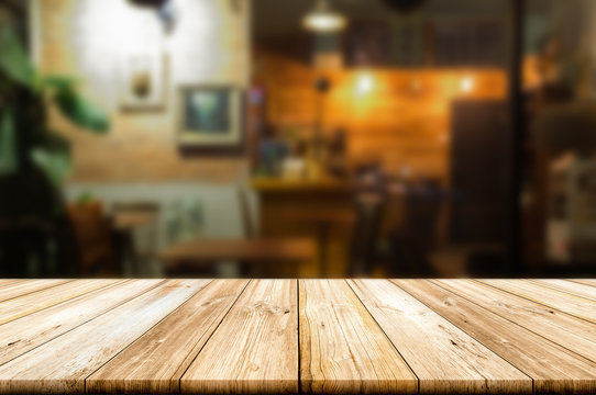 Empty wooden table top with blur coffee shop or restaurant interior background.