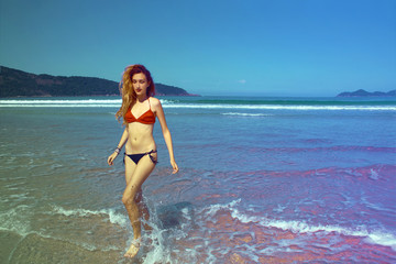 young woman in swimsuit running along the seashore, Brazil