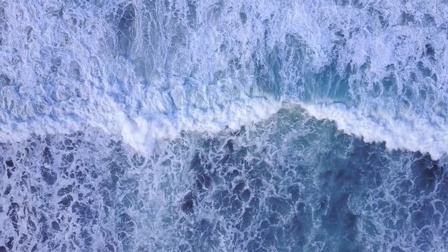 4K aerial view waves breaking on the rocks - cinematic colors at sunrise. Amazing nature aerial shot - scenic background elemental power