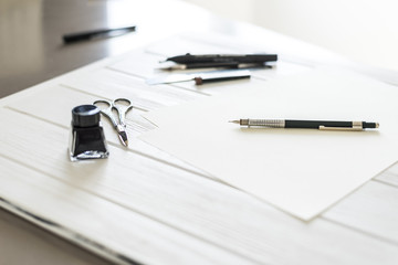 Design studio. Designer's attributes on table: scissors, pencil, pen etc. 