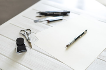 Design studio. Designer's attributes on table: scissors, pencil, pen etc. 