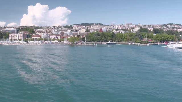 Lausanne city cinematic aerial shot. Camera flying over the lake and rising to discover the city in the background