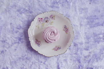 blueberry marshmallow flat lay on a  plate with flowers, over lilac background