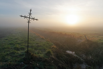 Obraz premium Wrought iron cross in misty field. Le Coudray-Montceaux village