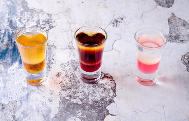 Set of strong alcoholic drink in shot glasses shooters, shots on background restaurant. Bar alcoholic cocktails menu into small glasses, long drink for party.
