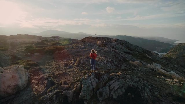 Amazing and epic inspirational aerial drone shot of female photographer make landscape photos of sea ocean and mountain cliffs,standing on edge, travel destination lifestyle blogger adventure seeker