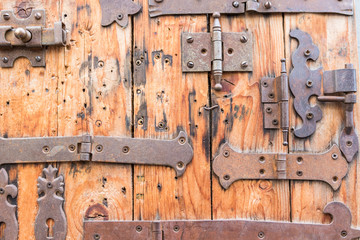 Different lockers, knobs and iron hinges on wooden door..