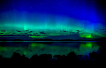 Fototapeta na wymiar Northern lights dancing over calm lake. Farnebofjarden national park in Sweden.