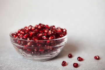 Red pomegranate in glass bowl on gray background