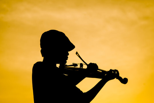 Silhouette boy playing  violin with sun set.