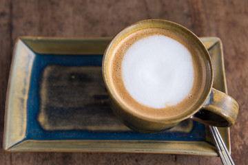 Hot coffee cappuccino cup with plate and spoon on wooden table