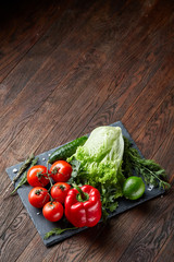 Vegetarian still life of assorted fresh vegetables and herbs on vintage wooden background, top view, selective focus.