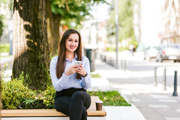 Fototapeta premium Young beautiful businesswoman drinks coffee and use cellphone