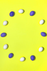 Frame of white and violet easter eggs on yellow background, copy space. Healthy food concept. Top view, flat lay. Happy Easter concept