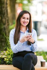 Young beautiful businesswoman drinks coffee and use cellphone