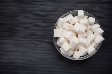 White sugar cubes in round bowl on black background