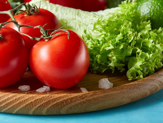 Refreshing close-up still life of assorted fresh vegetables and herbs on blue background, top view, selective focus.