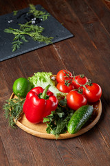 Close-up still life of assorted fresh vegetables and herbs on vintage wooden background, top view, selective focus.