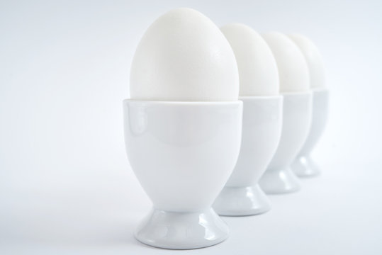 White eggs standing on egg cup isolated on white background, copy space. Row of boiled eggs in stand. Healthy food concept