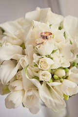 Two wedding gold rings on a wedding white bouquet