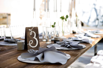 Table with food and flowers on the wedding. Number 3 written on white card stands before the bouquet in the center of dinner table