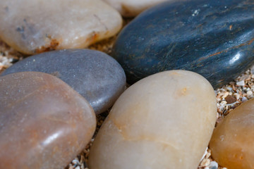 pebbles. clean white brown black pebbles isolated. the pebbles are on white or brown sand. small and large are visible