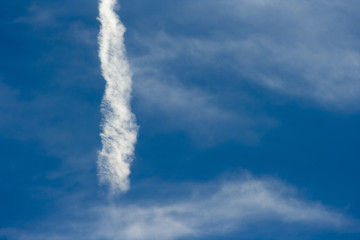 A beautiful blue sky with a dispersed streak of a flying airplane..