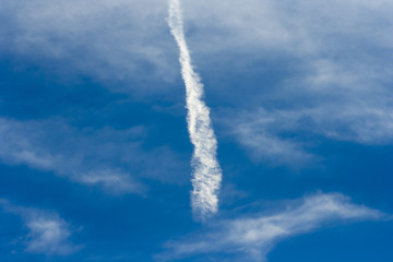 A beautiful blue sky with a dispersed streak of a flying airplane..